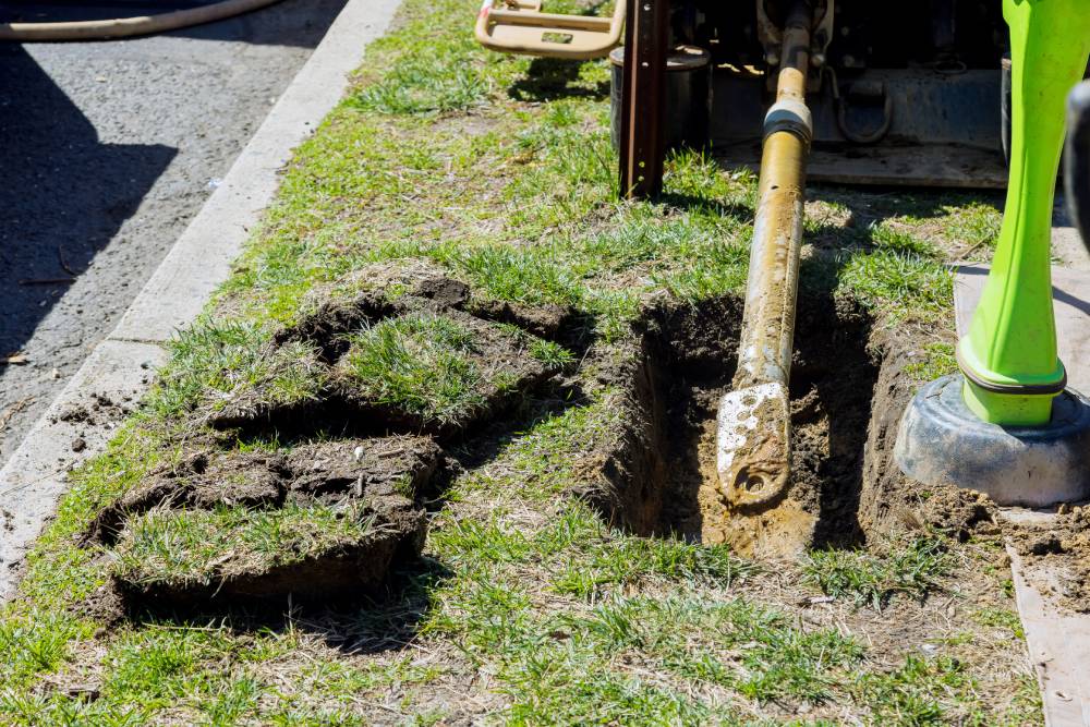 Trenchless sewer repair in progress beside a lawn.